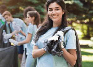 Happy woman with friends collecting recyclable litter in park
