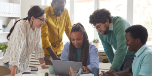 Group of co-workers gathered around computer