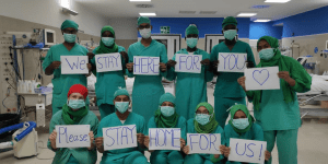 EMERGENCY USA medical staff during COVID-19 holding signs that read We stay here for you (heart), please stay home for us! - Answering the Call