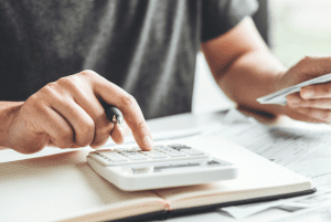 Person using calculator and handling documents - How the CARES Act, as supplemented by the Consolidated Appropriations Act of 2021, Impacts Charitable Giving